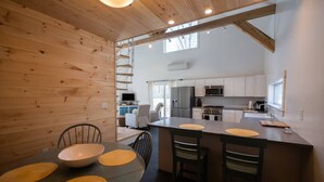 Una cocina moderna con armarios de madera, una isla central y una zona de comedor con una mesa redonda y sillas.