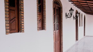 A corridor with brick walls, wooden doors, and a tiled floor. - House on the Island of Itaparica Bahia, with swimming pool and complete gourmet space (VERA CRUZ)