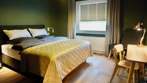 Een slaapkamer met een bed, een bureau en een stoel.
