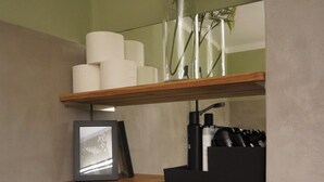 Een badkamer met houten planken met handdoeken, toiletartikelen en een lijst met een foto.