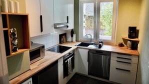 Een moderne keuken met witte kasten, een houten aanrecht, een ingebouwde oven, een vaatwasser en een raam met uitzicht op groen.
