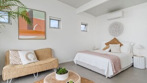 Une chambre à coucher moderne avec un lit, un canapé et une petite plante en pot.