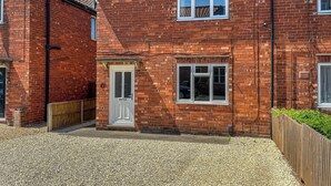A two-story brick house with a white door, a small window, and a visible number '14' on the wall. - 2 bedroom accommodation in Lincoln (Lincoln)