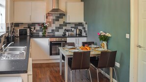 A compact kitchen with modern appliances, a dining area with a table set for two, and a small oven. - 2 bedroom accommodation in Lincoln (Lincoln)