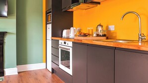 Una cocina moderna con armarios oscuros, una encimera de madera y un horno empotrado.
