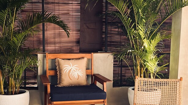 Un rincón acogedor con una silla de madera, un banco acolchado y un tapete de fibras.