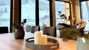 Un interior de madera con ventanas amplias, una mesa con velas y un jarrón con plantas.