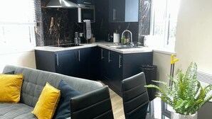 A modern kitchen with dark cabinets, a built-in oven, and a window. - Leeds Urban Retreat- Pet Friendly Flat (Leeds)