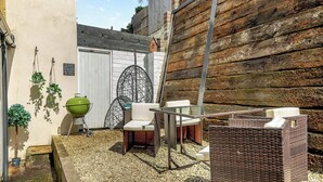 Un patio con una parrilla, asientos exteriores y una pared de madera.