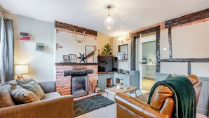 Una sala de estar acogedora con chimenea de ladrillo, un sillón de cuero y un televisor.