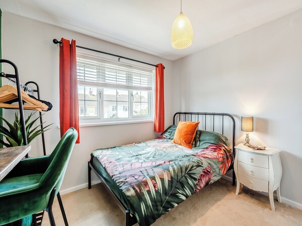 A bedroom with a bed, a bedside table, a lamp, a window with curtains, a chair, and a plant. - 2 bedroom accommodation in Bere Regis (Bere Regis)