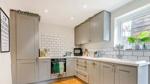 Una cocina moderna con gabinetes grises, encimera blanca y suelo de madera en espiga.