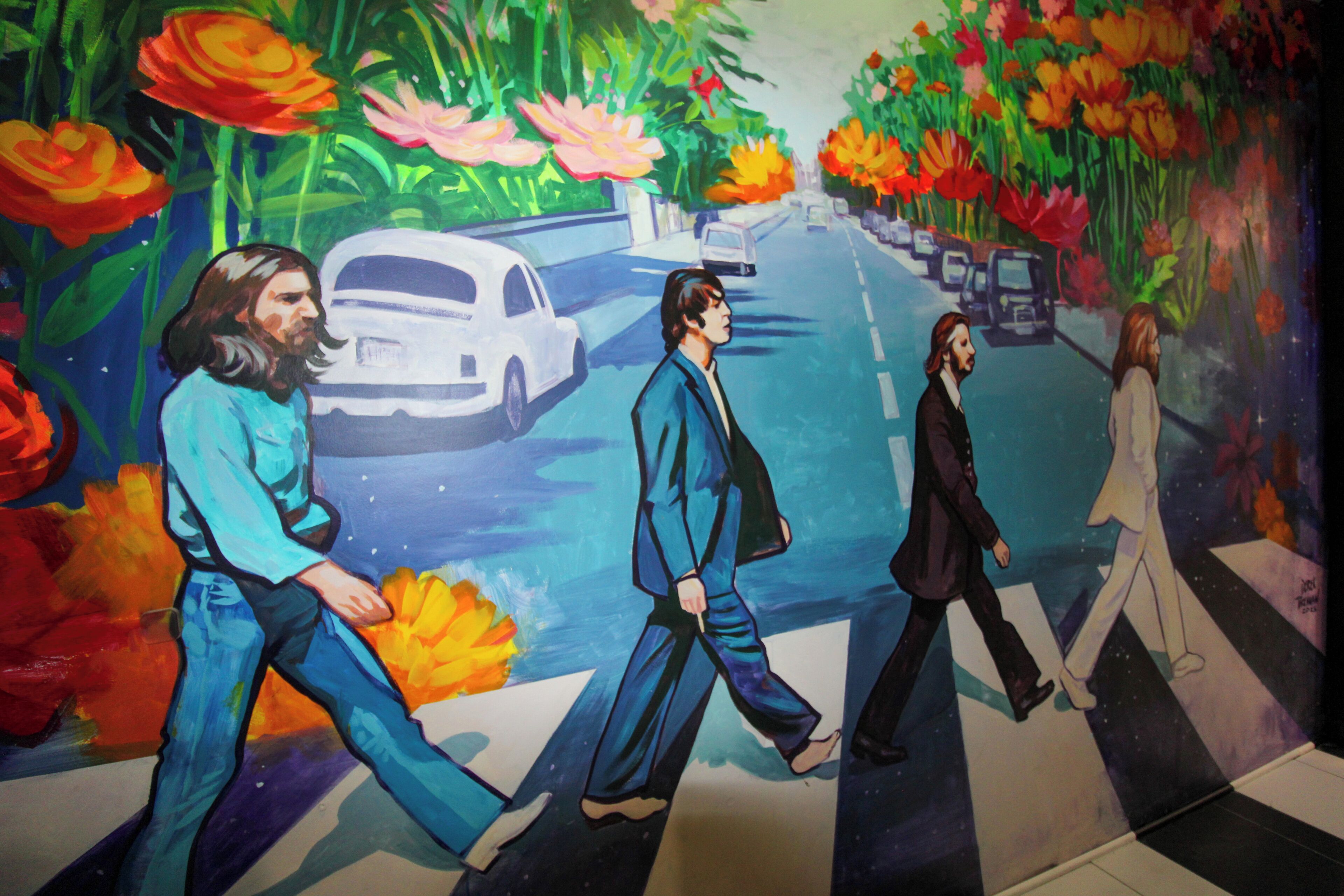 A mural with four figures crossing a street, surrounded by vibrant flowers and a white car.