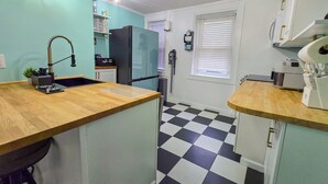 Una cocina compacta con piso a cuadros, un lavamanos con grifo moderno y un refrigerador.