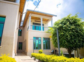 A two-story building with a balcony, a covered entrance, and a well-maintained garden. - The Vibrant Loadge (Kigali)