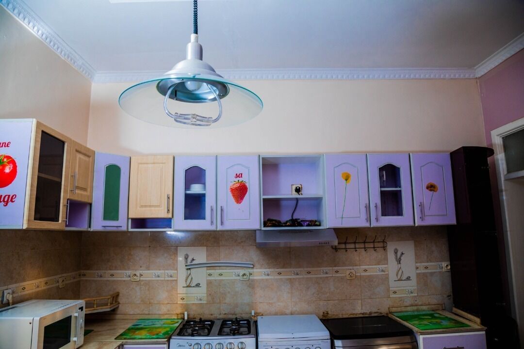 A kitchen with a gas stove, microwave, and cabinets with decorative stickers.
