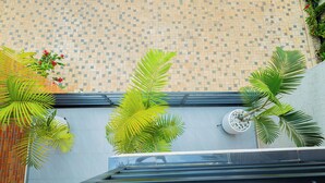 A tiled wall with a patterned design, a potted plant with red flowers, and a palm tree. - The Vibrant Loadge (Kigali)