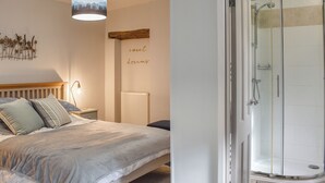 Un dormitorio con cama, mesita de noche, lámpara y una pared decorada con una pintura de un paisaje de montaña.