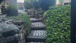 Un sendero de piedra que atraviesa un jardín con plantas en macetas y un farol.