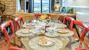 Une table à manger dressée avec des assiettes, des tasses et un saladier rempli de fruits.