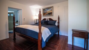 A bedroom with a four-poster bed, a nightstand, and a painting on the wall. - Private Studio Suite (Lakeland)