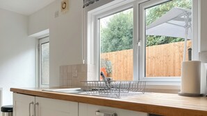 A kitchen with a wooden countertop, a built-in dishwasher, and a window with a view of a wooden fence and greenery. - 2 bedroom accommodation in Taff&rsquo;s Well, near Cardiff (Taff&rsquo;s Well, near Cardiff)