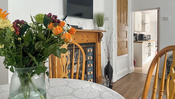 A living room with a fireplace, a television mounted on the wall, and a dining area with a table and chairs. - 2 bedroom accommodation in Taff&rsquo;s Well, near Cardiff (Taff&rsquo;s Well, near Cardiff)