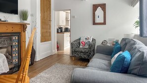 A living room with a grey sofa, a wooden door, a television, and a kitchen in the background. - 2 bedroom accommodation in Taff&rsquo;s Well, near Cardiff (Taff&rsquo;s Well, near Cardiff)