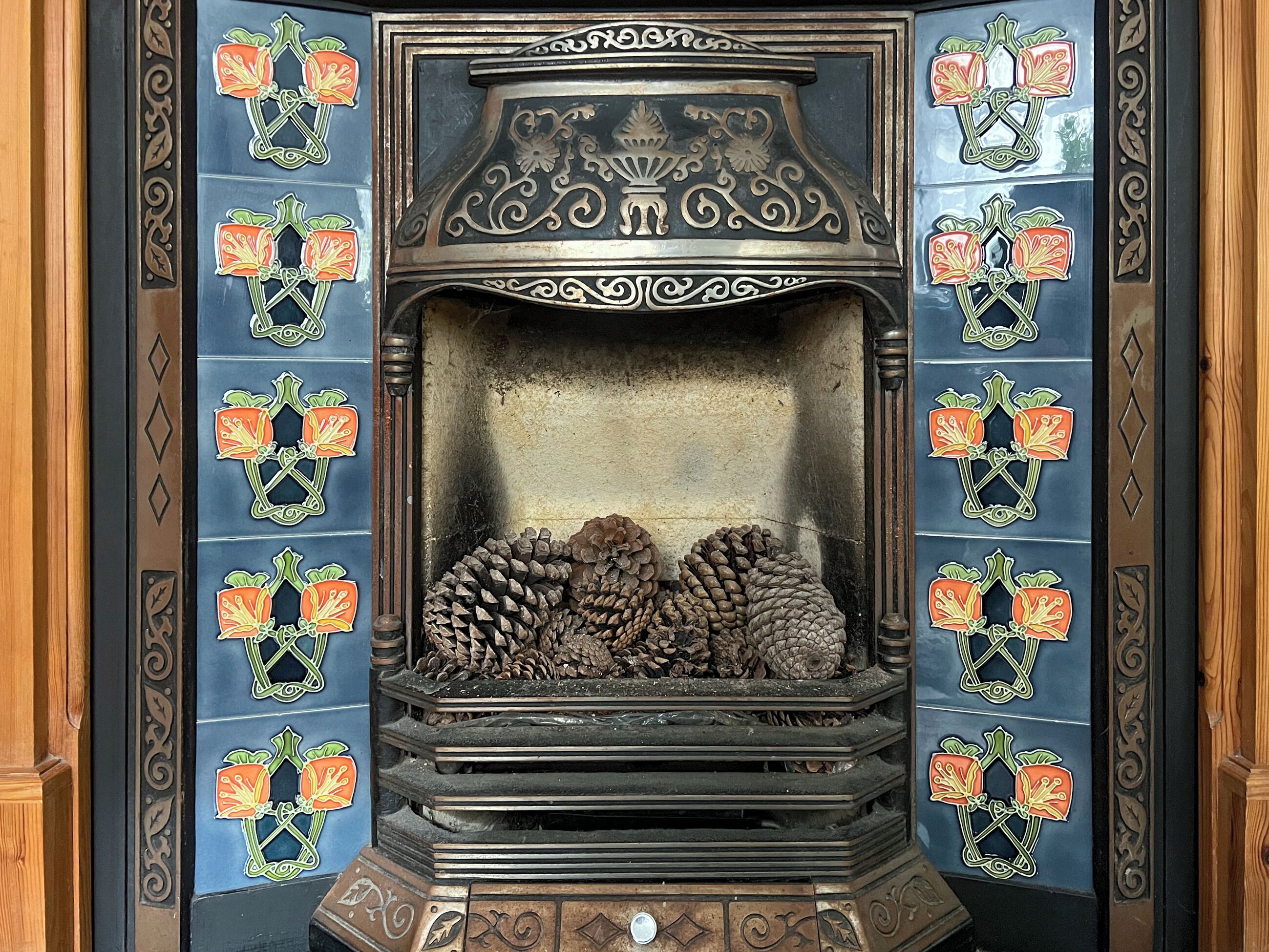 A fireplace with intricate metalwork and decorative tiles.