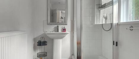 A bathroom with a white sink, mirror, and shower.