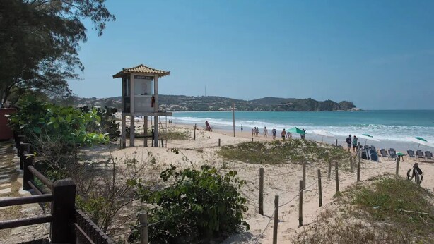 Platja amb una torre de socorristes, sorra i oceà.