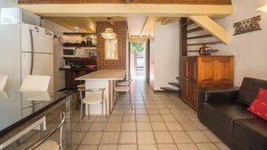 Una cuina moderna amb una illa central, zona de dinar amb caires, un sofà de pell negra i una escala que condueix a un altre nivell.