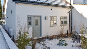 A white house with a tiled roof, a front door, and two windows.