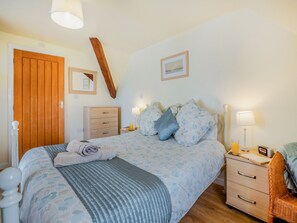 A bedroom with a bed, bedside tables, a wardrobe, and a mirror.