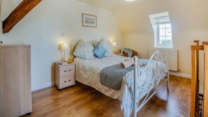 Une chambre à coucher avec un lit, des tables de chevet, une fenêtre et un radiateur.