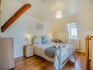 A bedroom with a bed, bedside tables, a window, and a radiator.