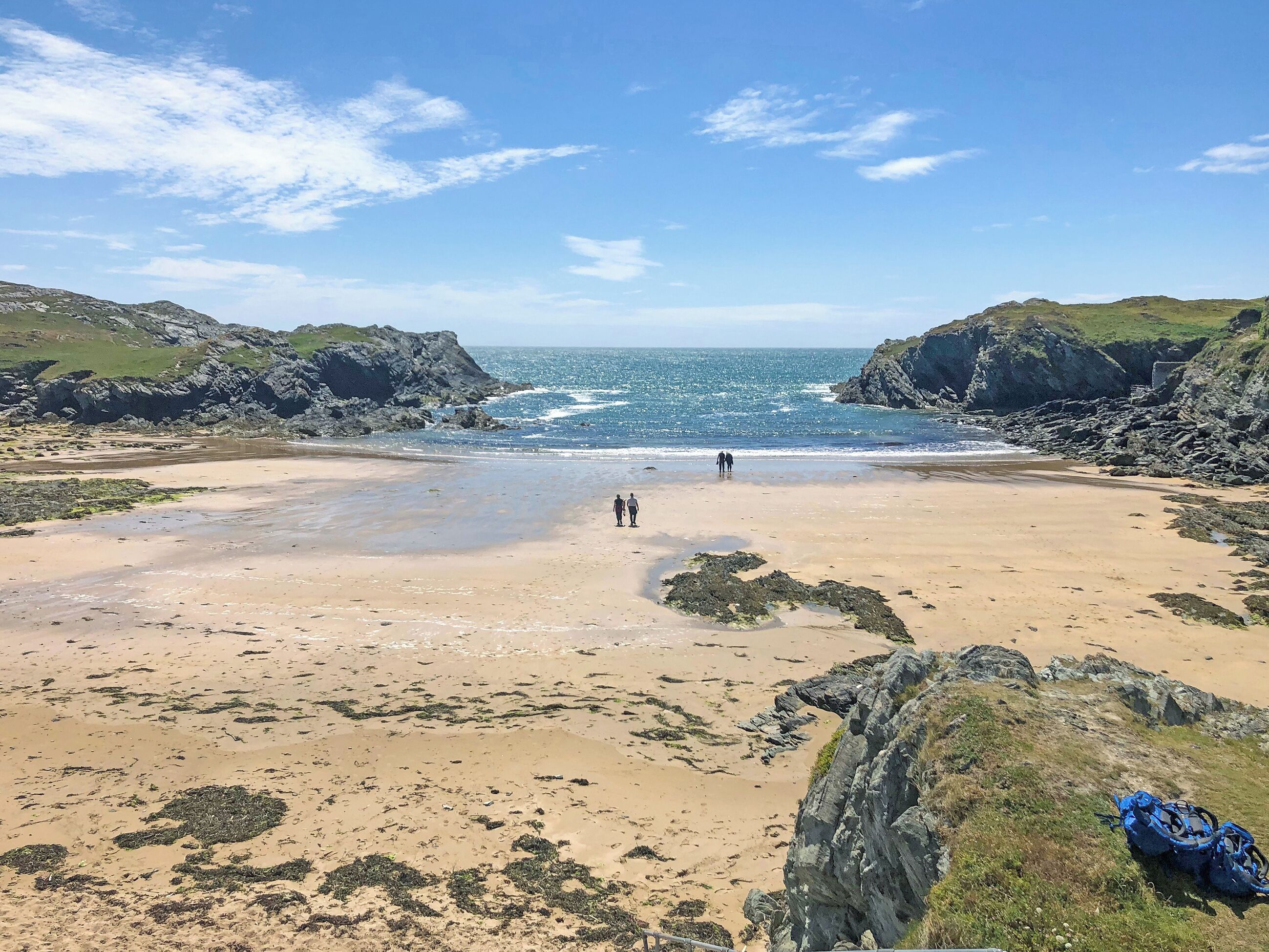 A beach with rocky cliffs and a clear sky.