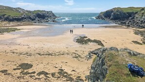 Une plage bordée de falaises rocheuses, sous un ciel dégagé.