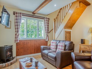 A cozy living room with a leather sofa, a fireplace, and a wooden staircase.