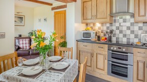 Une cuisine moderne avec des meubles en bois, un four à micro-ondes et une cuisinière. On y trouve une table à manger, dressée avec des assiettes et agrémentée d'un vase de fleurs.