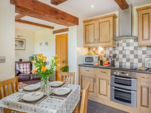 Une cuisine moderne avec des meubles en bois, un four à micro-ondes et une cuisinière. On y trouve une table à manger, dressée avec des assiettes et agrémentée d'un vase de fleurs.