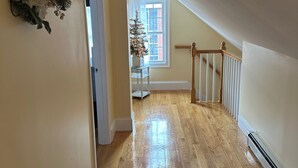 Un pasillo con suelo de madera, una escalera y un árbol de Navidad junto a una ventana.