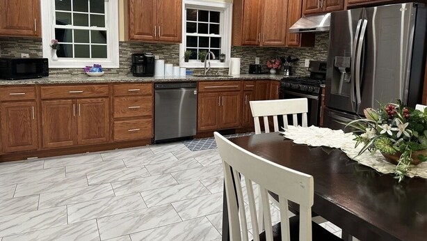 Una cocina moderna con armarios de madera, un refrigerador de acero inoxidable y un comedor con mesa y sillas.