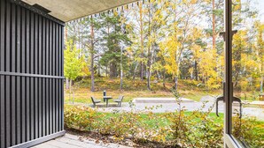 A covered outdoor area with a view of a forest in autumn. - Cozy Haven Minutes From Central (Stockholms län)