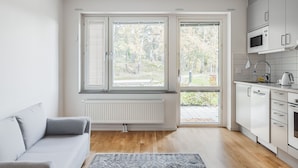 A modern kitchen with white cabinets, a microwave, and a kettle. - Cozy Haven Minutes From Central (Stockholms län)