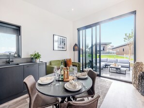 A modern kitchen with a dining area, large windows, and a view of the outside. - Cybi Lodge 6 - UK42798 (Llangefni)