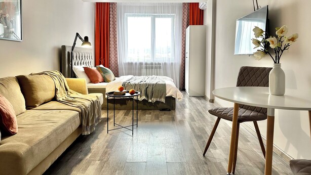 A modern living room with a sofa, a bed, a small table, and a TV.