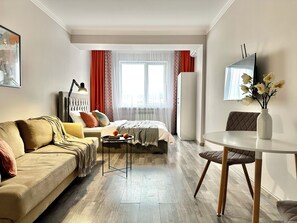 Una sala moderna con un sofá, una cama, una mesita y un televisor.