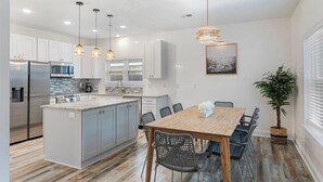 A modern kitchen with a central island, stainless steel appliances, and pendant lighting. - PCB Paradise Sands Oasis - Private Pool, Game Room, Hot Tub! (Panama City Beach)