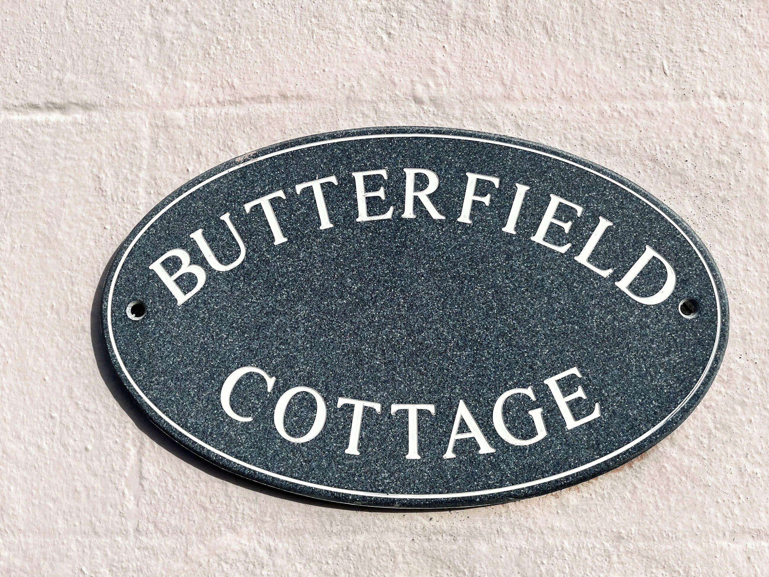 A sign with the text "BUTTERFIELD COTTAGE" on a textured surface.